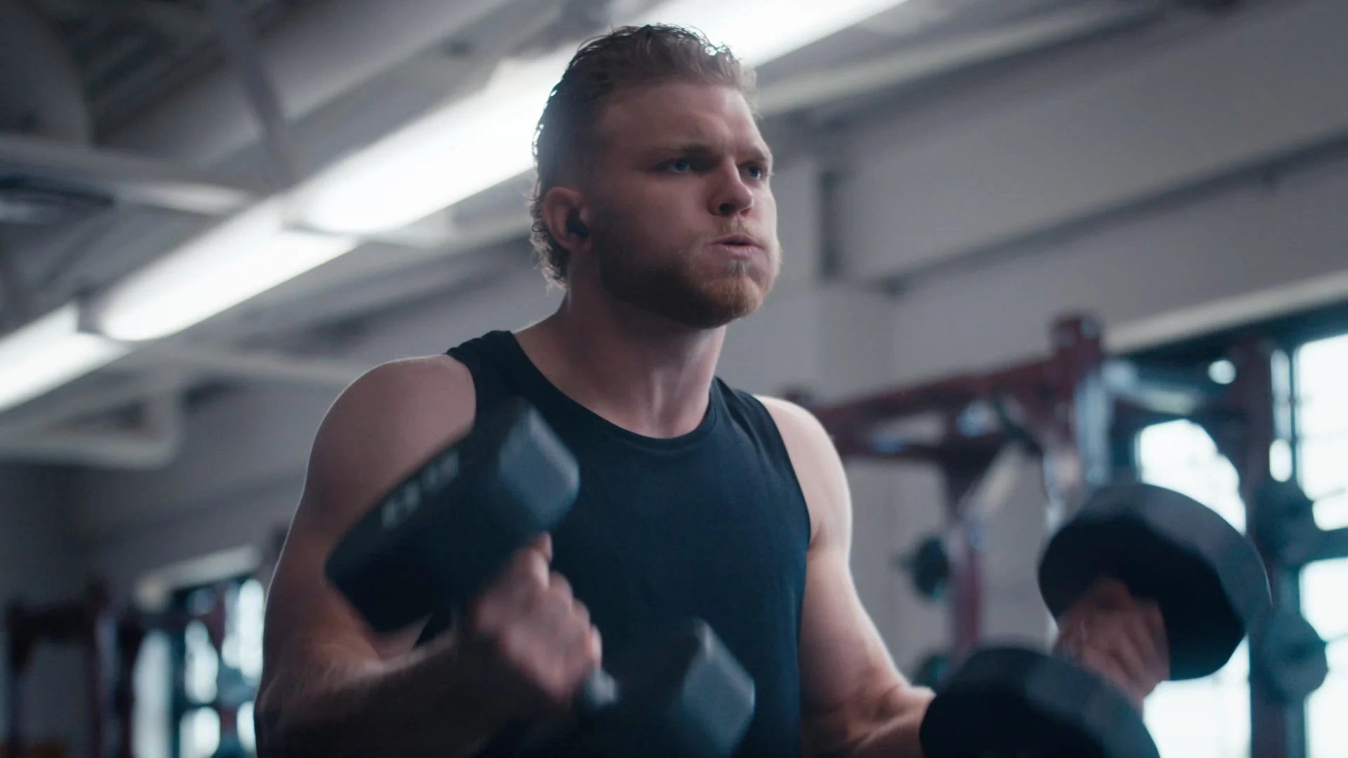 Aidan Hutchinson curling dumbbells in a gym